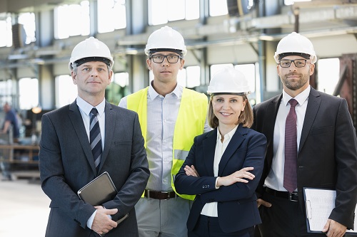 Team of confident business people wearing hardhats in metal industry